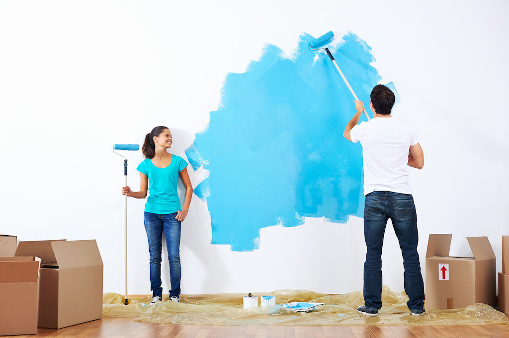 Couple painting apartment wall blue
